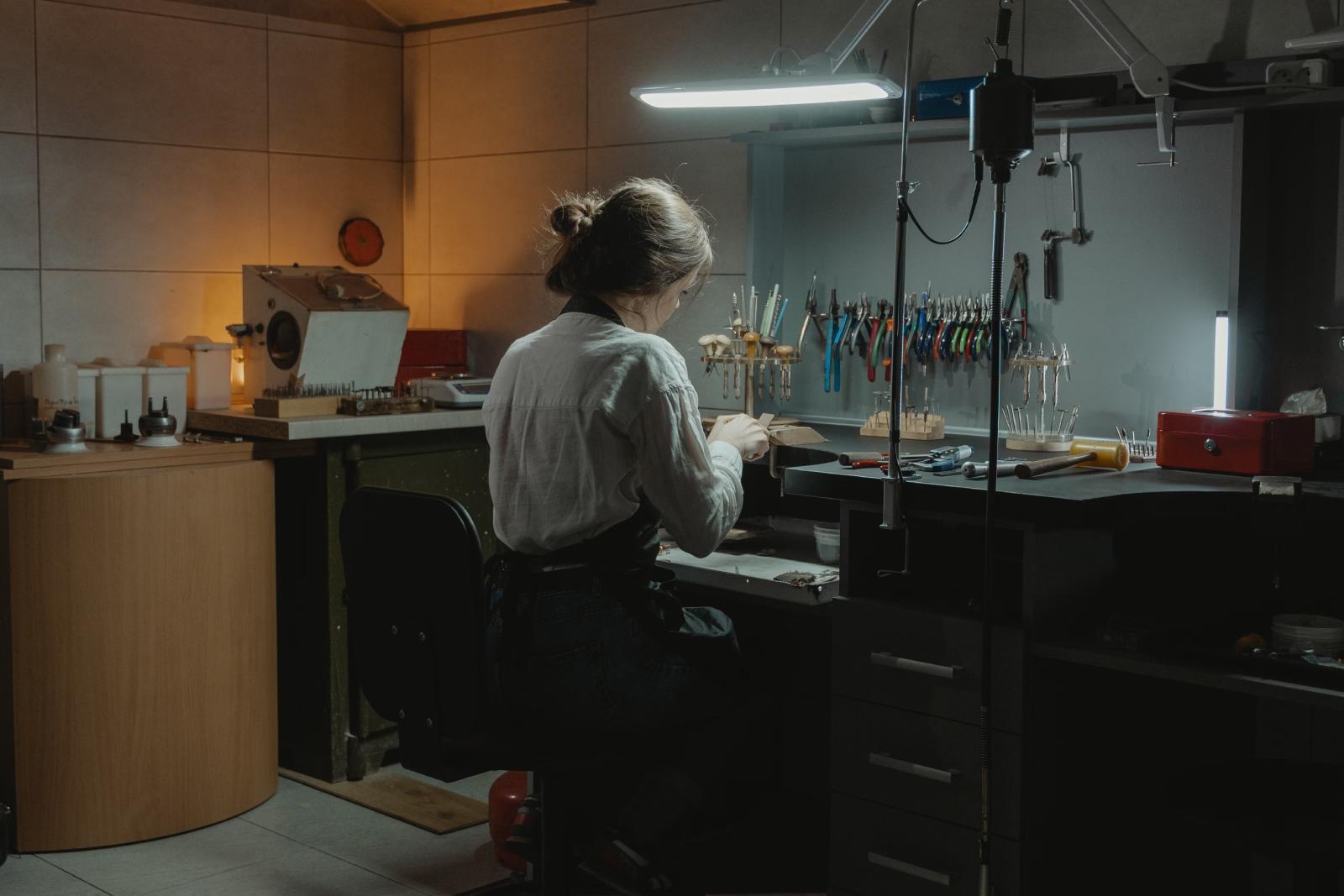 Joyero revisa en su banco de trabajo la facturación y los márgenes de su joyería en una tableta