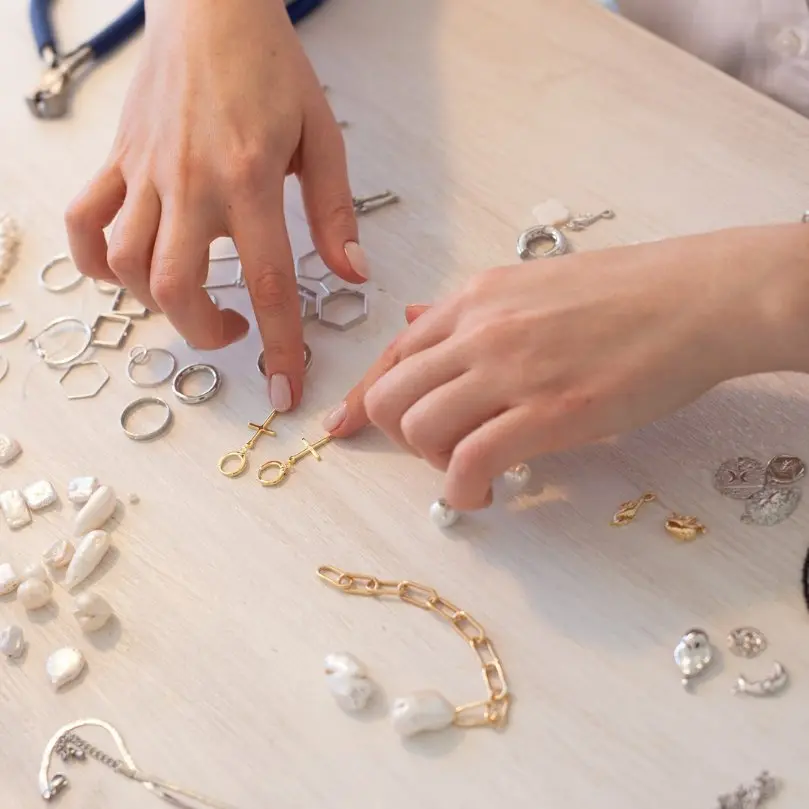 Juwelier die werkt met verschillende sieraden, onderdelen en parels op een werktafel